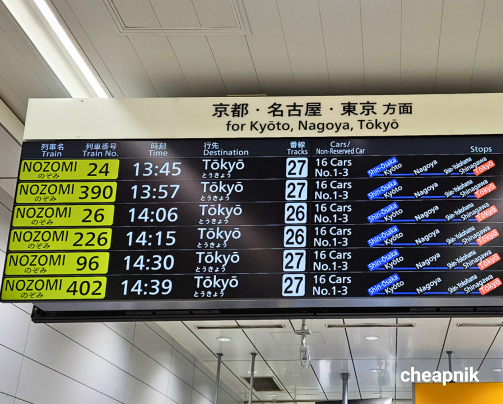 Shinkansen signage showing the Nozomi train with train number, time, destination, track number, cars, and stops along the route